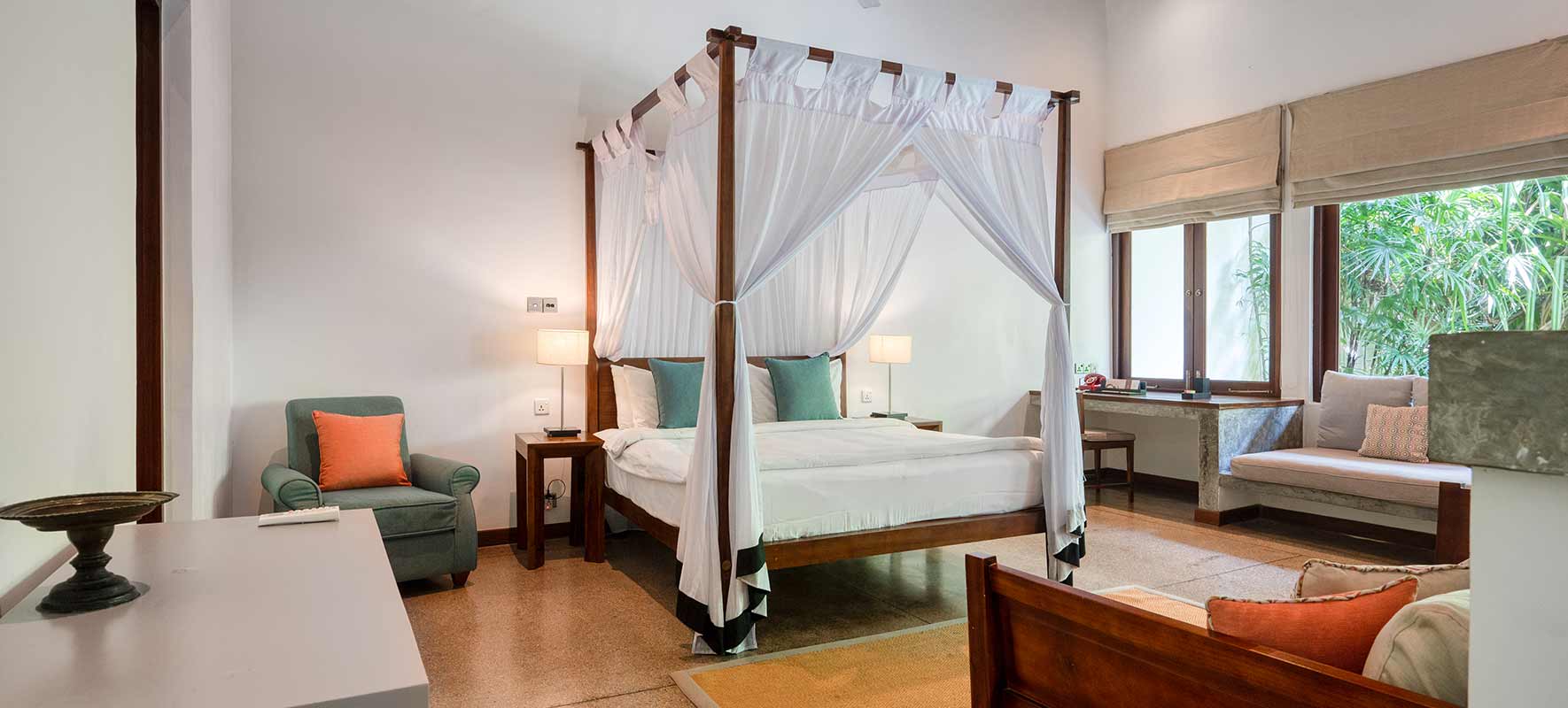 The Mountbatten Suite bedroom, a four-poster bed under white netting and a window onto the garden