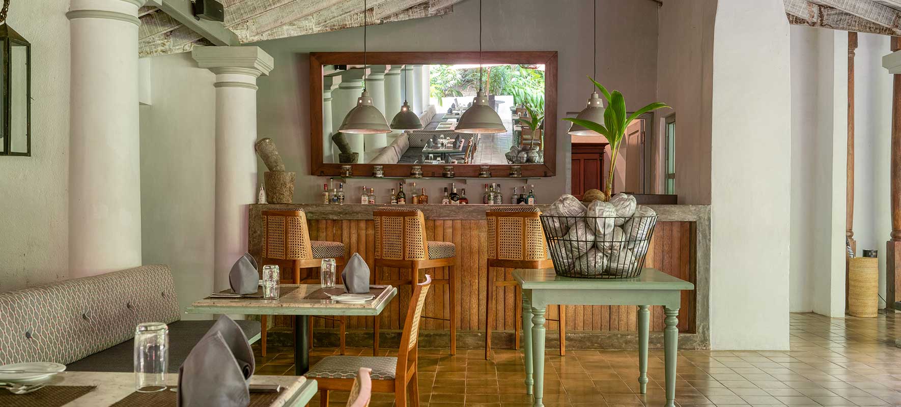 The restaurant, laid tables between white columns in front of a timber bar