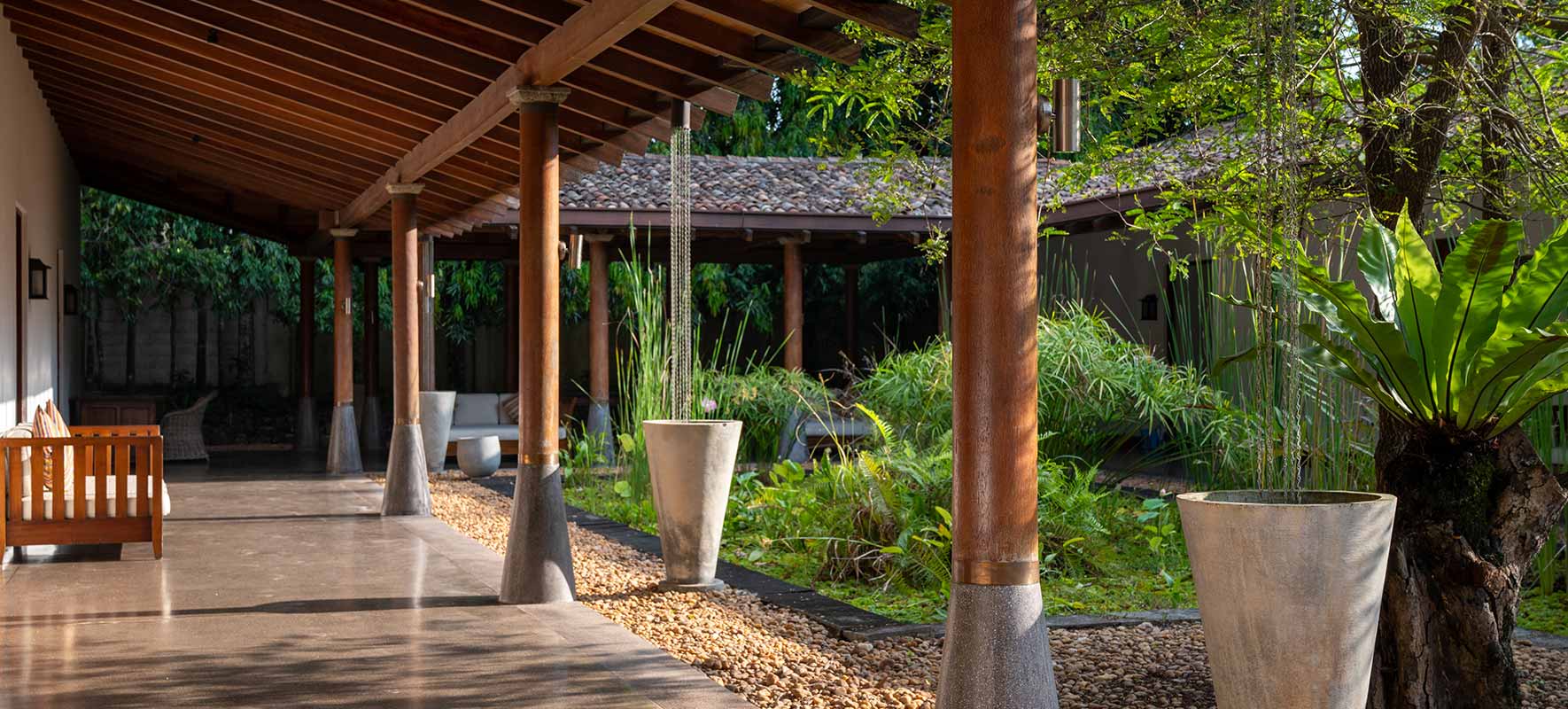 A long covered verandah on timber columns beside a planted courtyard